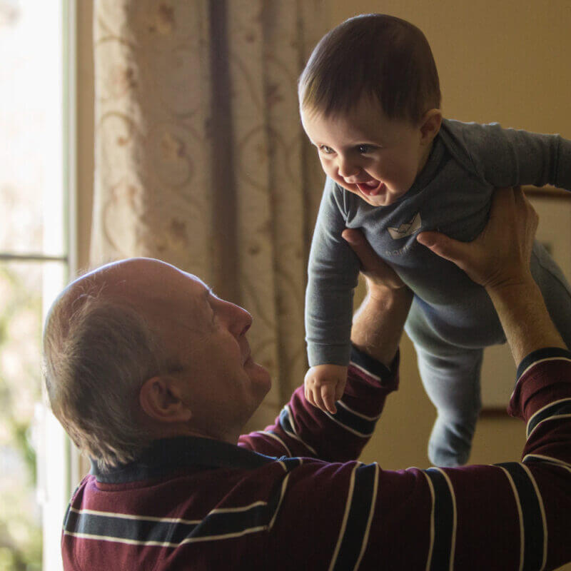 Grandfather lifting his happy infant grandchild into the air