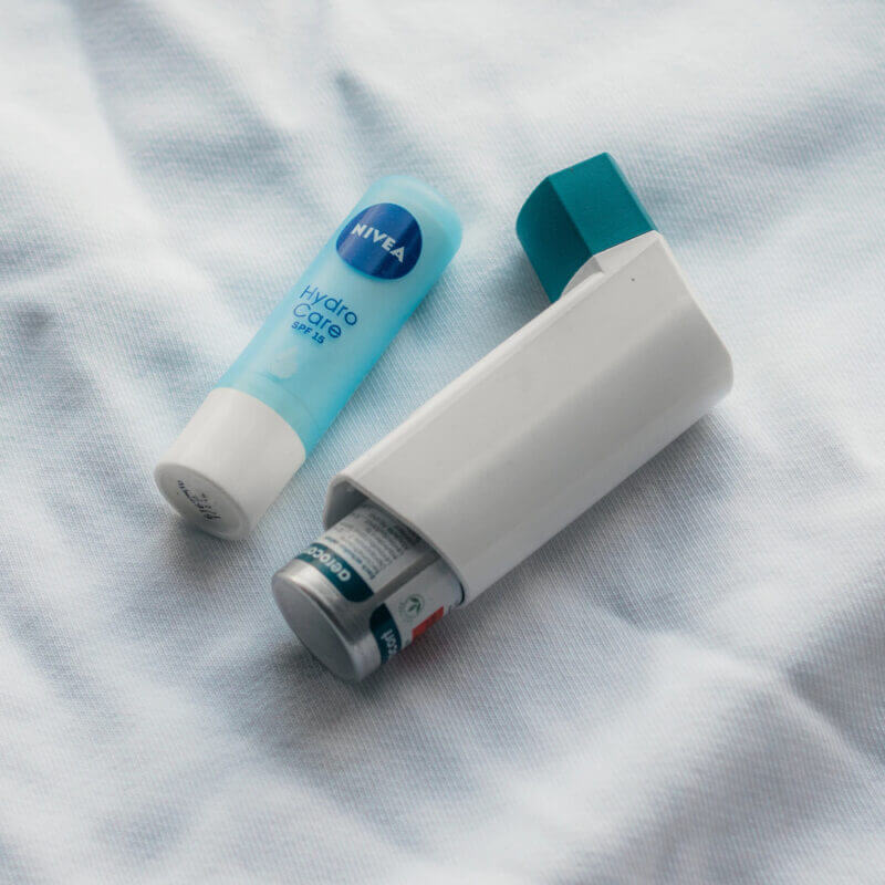 An inhaler and medication laying atop a white cloth