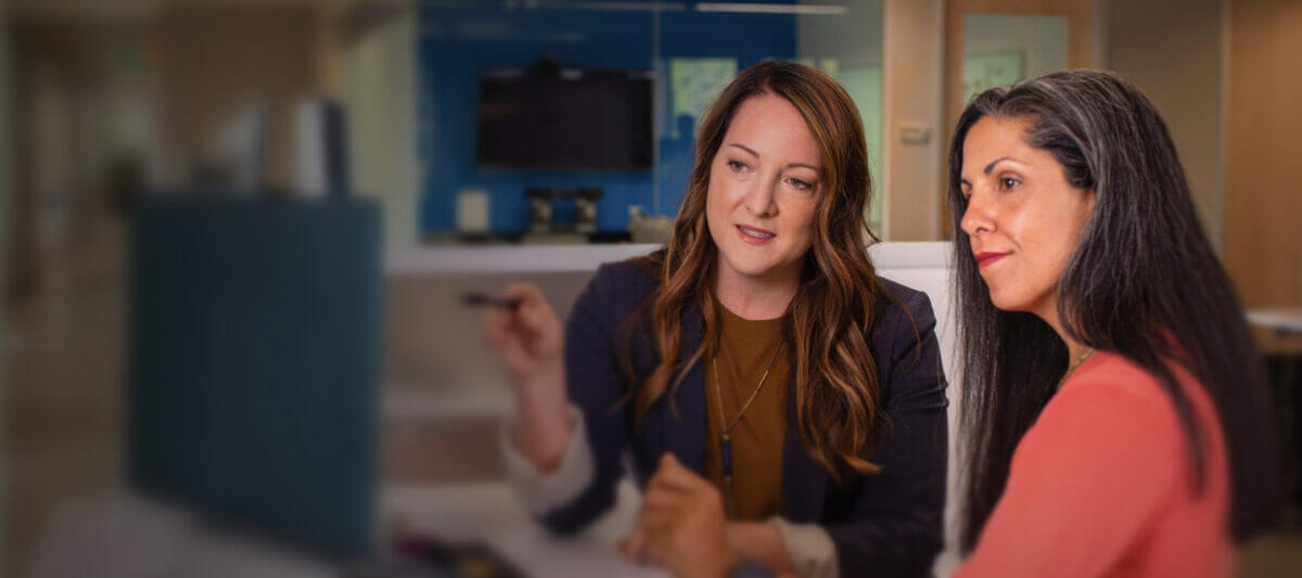Business professionals discussion something in front of a computer, in a clinical setting