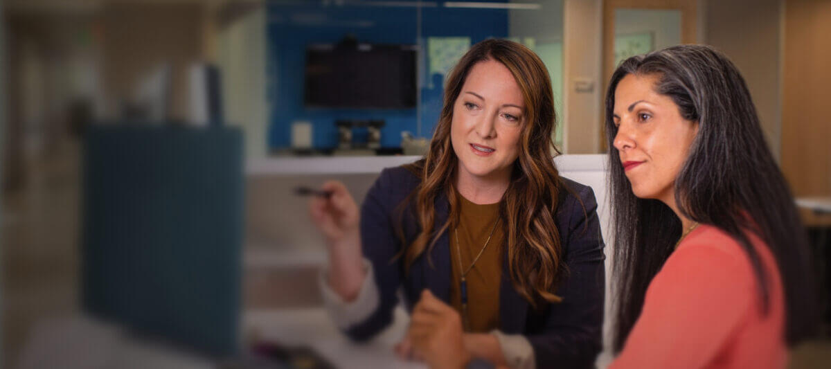 Business professionals discussion something in front of a computer, in a clinical setting