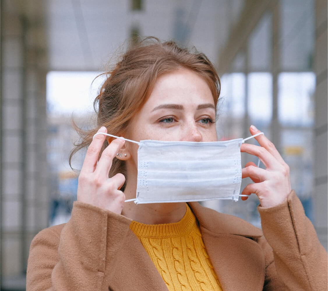 Woman, outdoors, putting on basic face mask for COVID protection