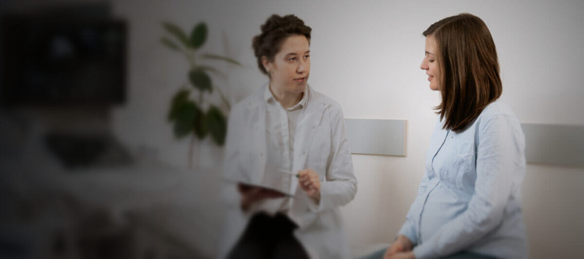 OB/GYN doctor speaking with patient next to ultrasound scanner